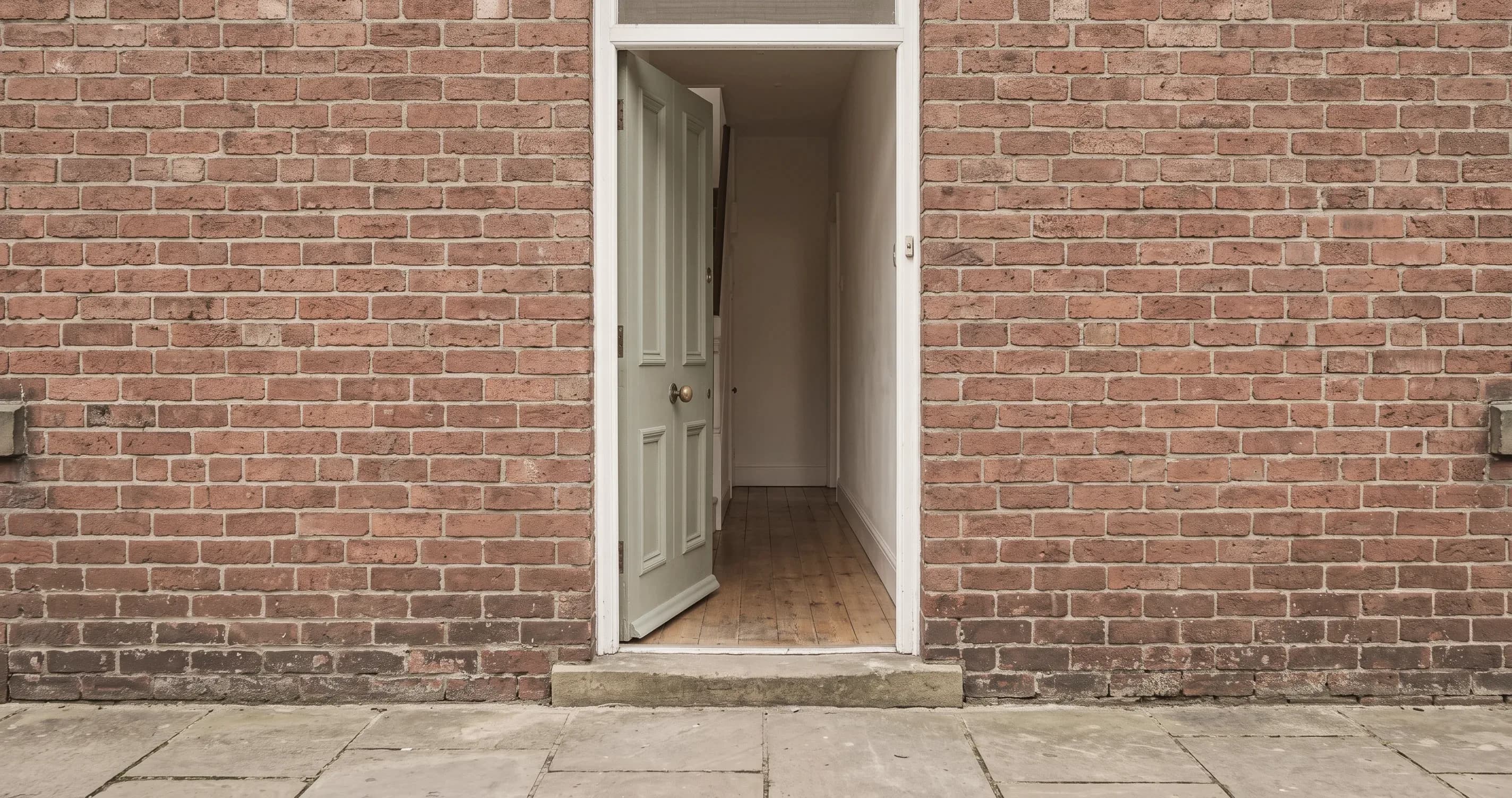 An open front door with an empty hallway beyond it.