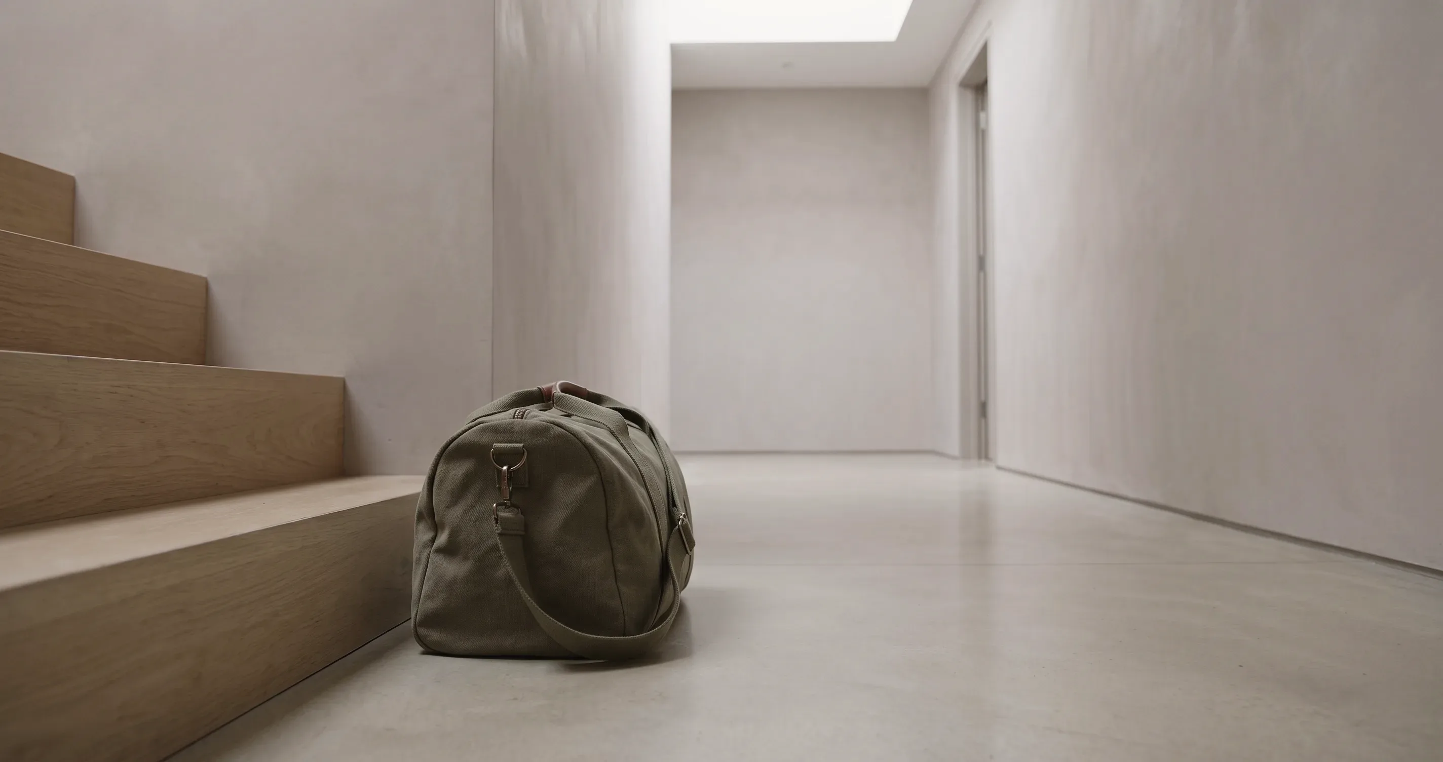 A gym bag sitting unopened at the bottom of a staircase.