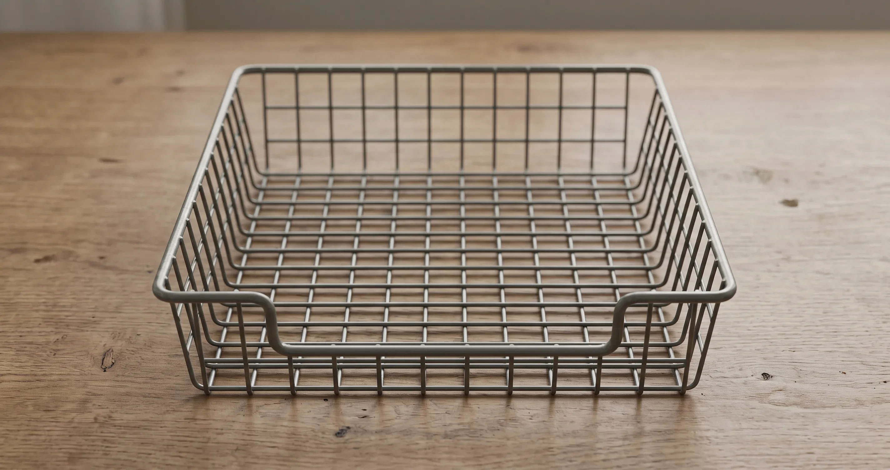 A wire in-tray on a desk, empty.