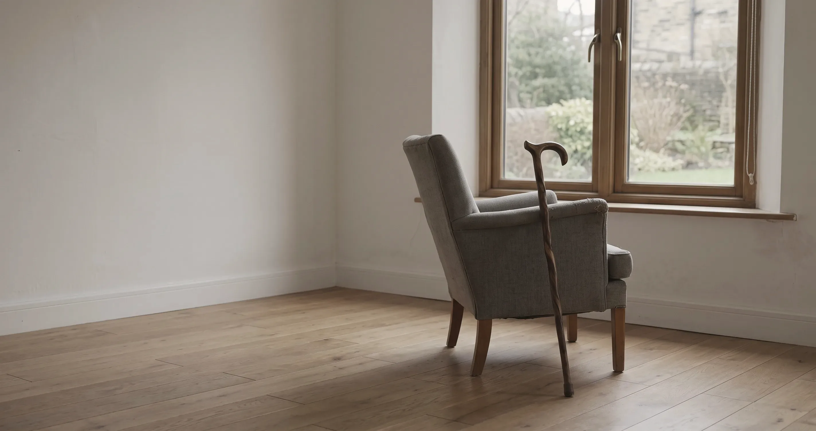 A walking stick propped against a chair by a window.