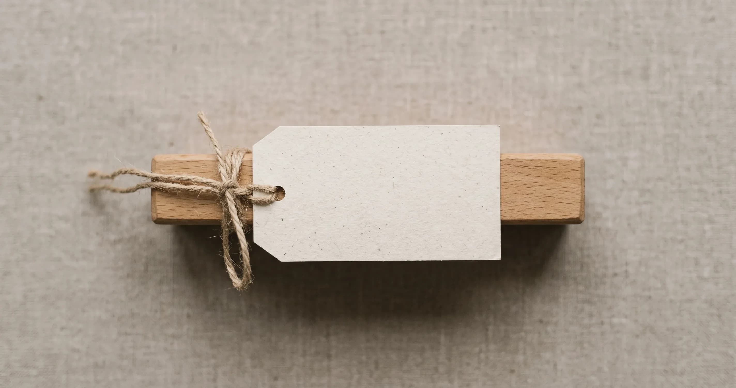 A blank luggage label tied to a plain wooden handle.