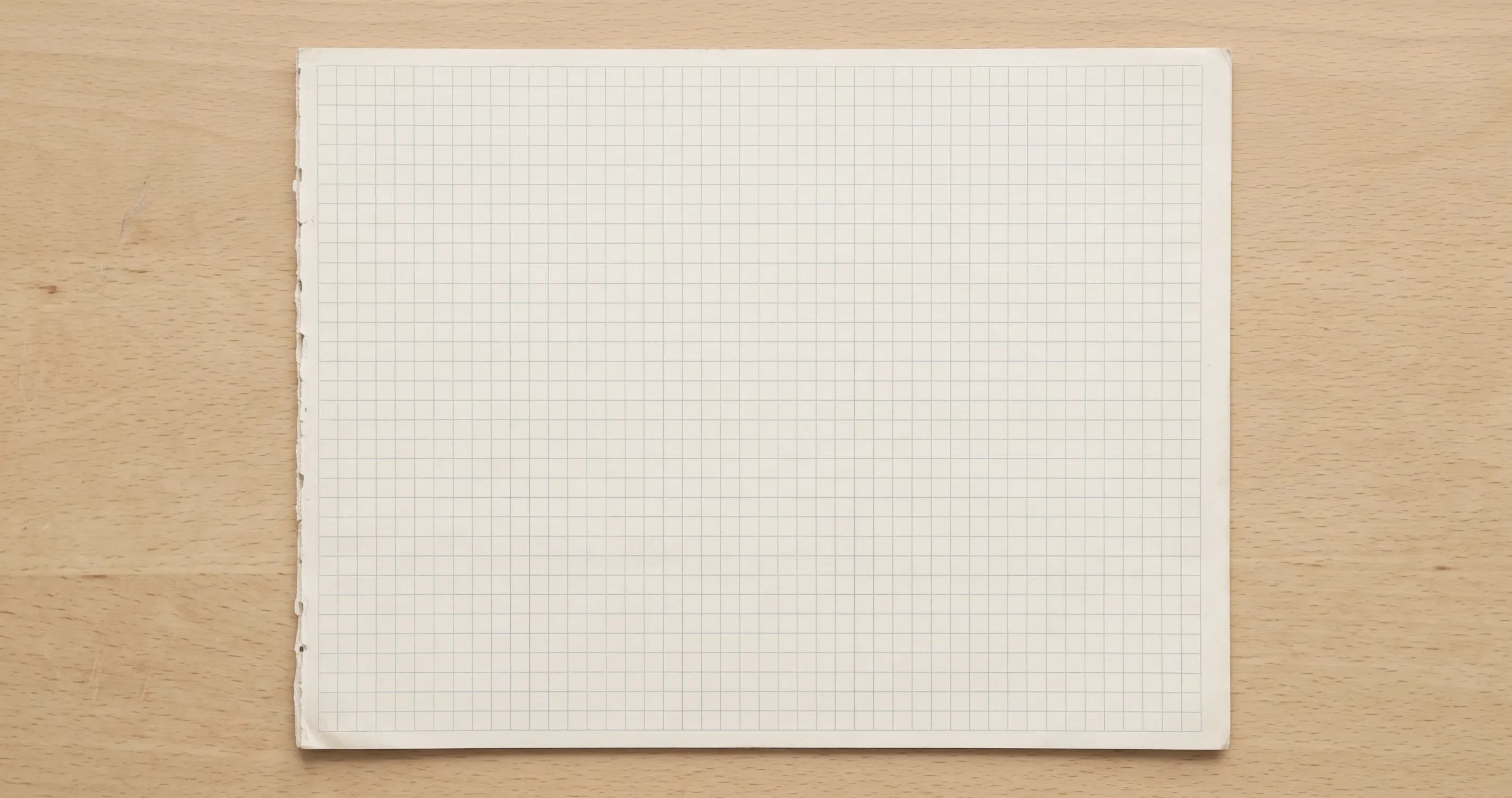 A sheet of squared graph paper on a plain desk.