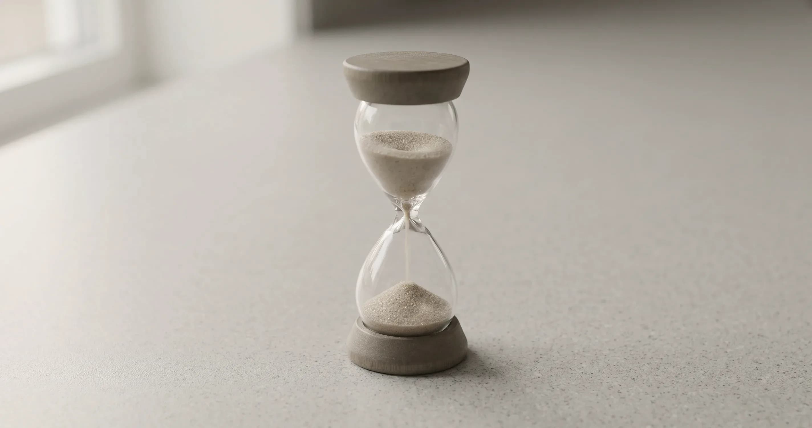 An egg timer on a plain kitchen worktop, sand partly run through.