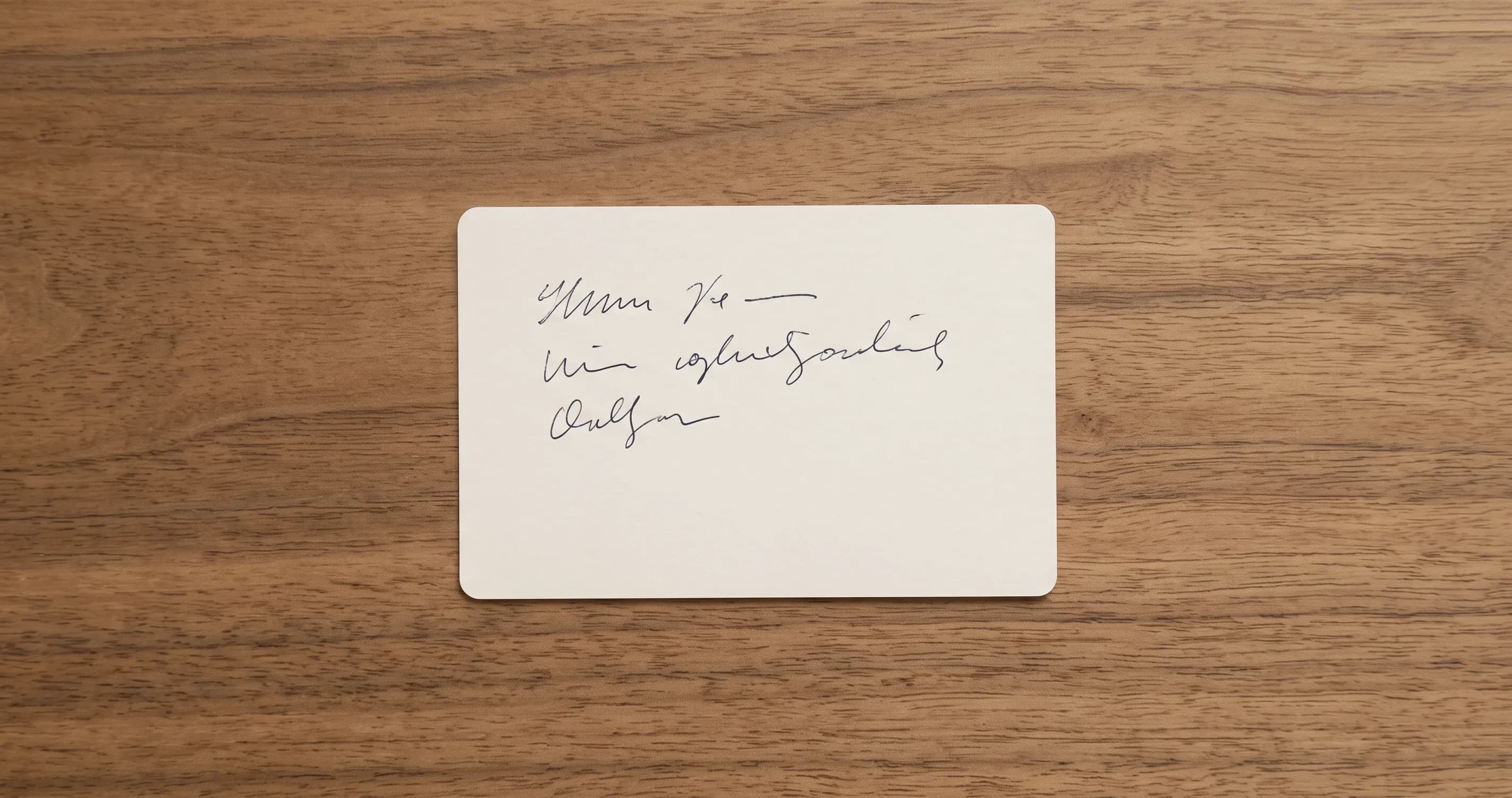 A plain index card lying on a wooden table with a few short handwritten lines on it.